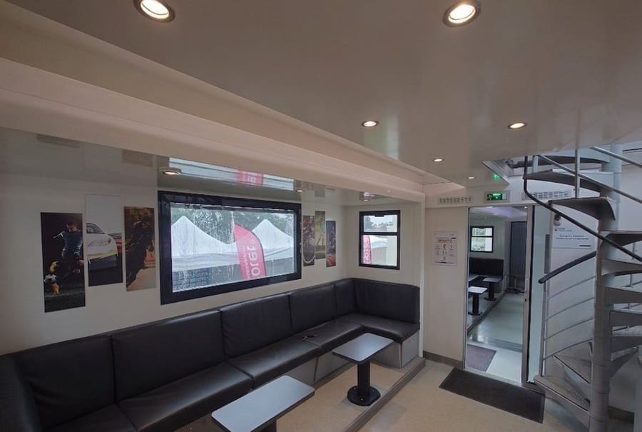 Intérieur VIP du Car-Podium avec bar courbe design, banquettes cuir, écran et climatisation