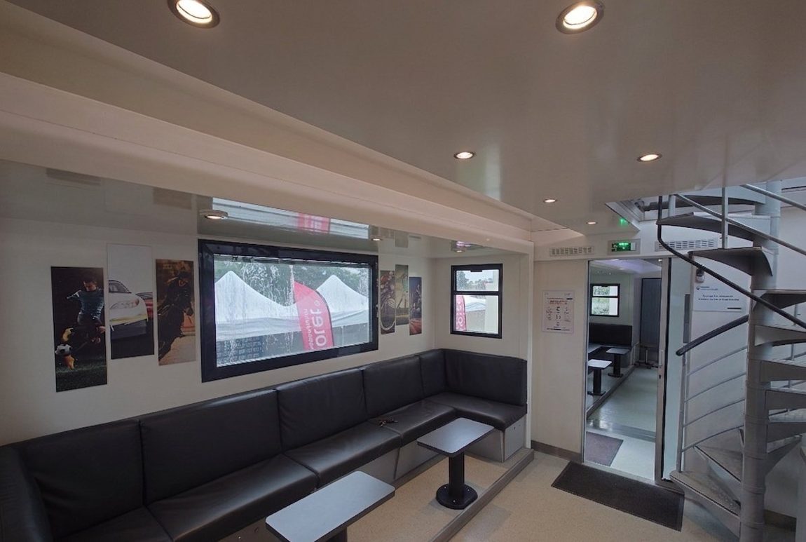 Intérieur VIP du Car-Podium avec bar courbe design, banquettes cuir, écran et climatisation
